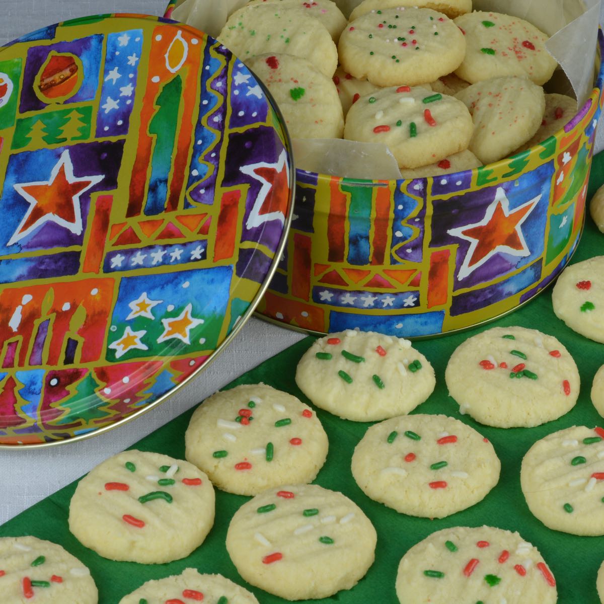 A tin of gluten free Whipped Shortbread decorated with red and green sprinkles.