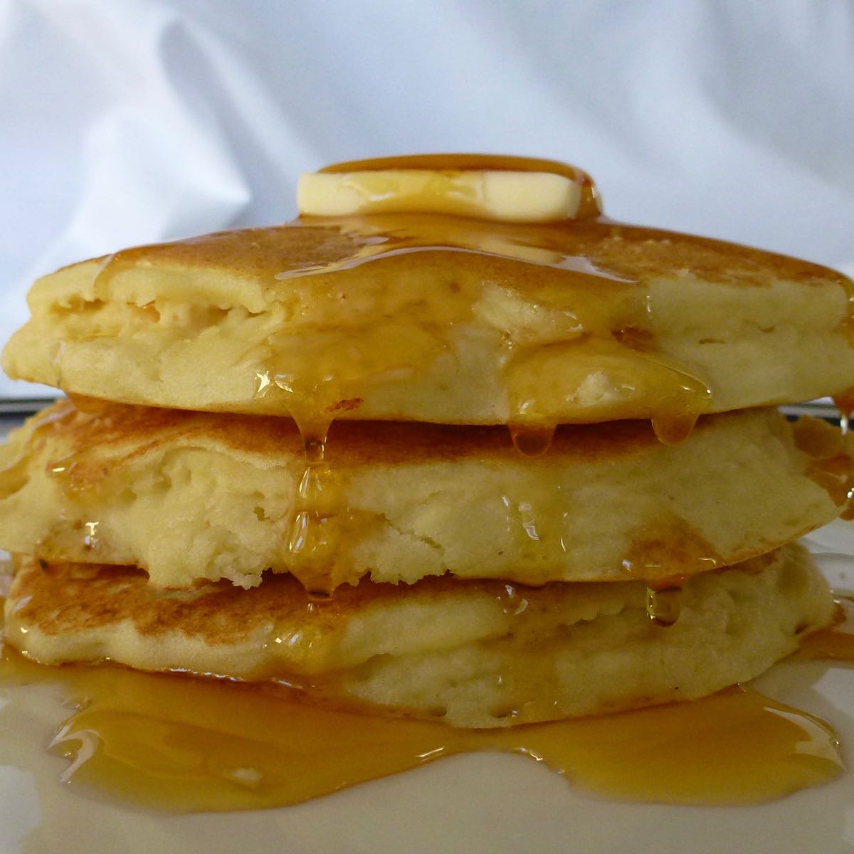 A stack of gluten free Yogurt Pancakes with syrup dripping down the sides.