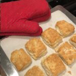 A baking pan of Buttermilk Biscuits with oven mitts at the side.