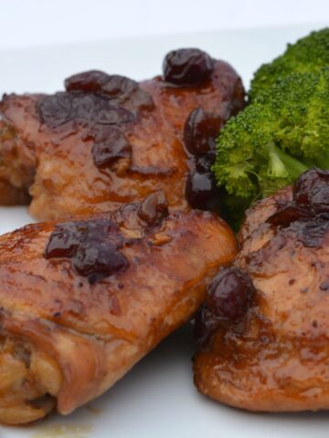 Three thigh pieces of gluten free Cranberry Orange Chicken and steamed broccoli.
