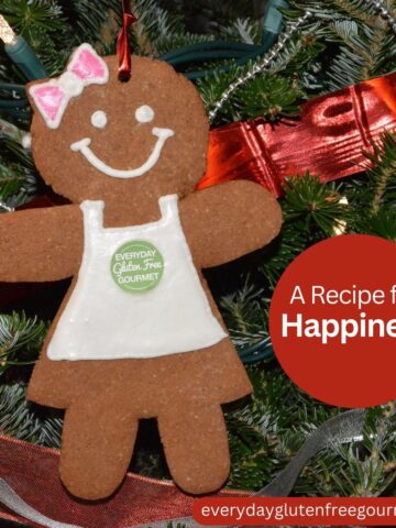 A gingerbread lady wearing a white apron with the Everyday Gluten Free Gourmet logo, hanging on a Christmas tree.