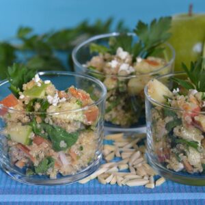 Individual dishes of Apple Quinoa Salad on a blue napkin surrounded by Granny Smith apples and slivered almonds.