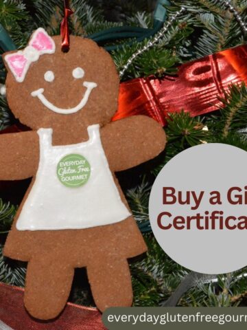 A gingerbread lady cookie wearing a white icing apron hanging on a Christmas tree beside a silver ornament saying Buy a Gift Certificate.