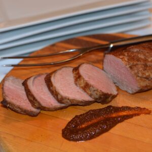 A cutting board with slices of a Pork Tenderloin with Asian Flavours.