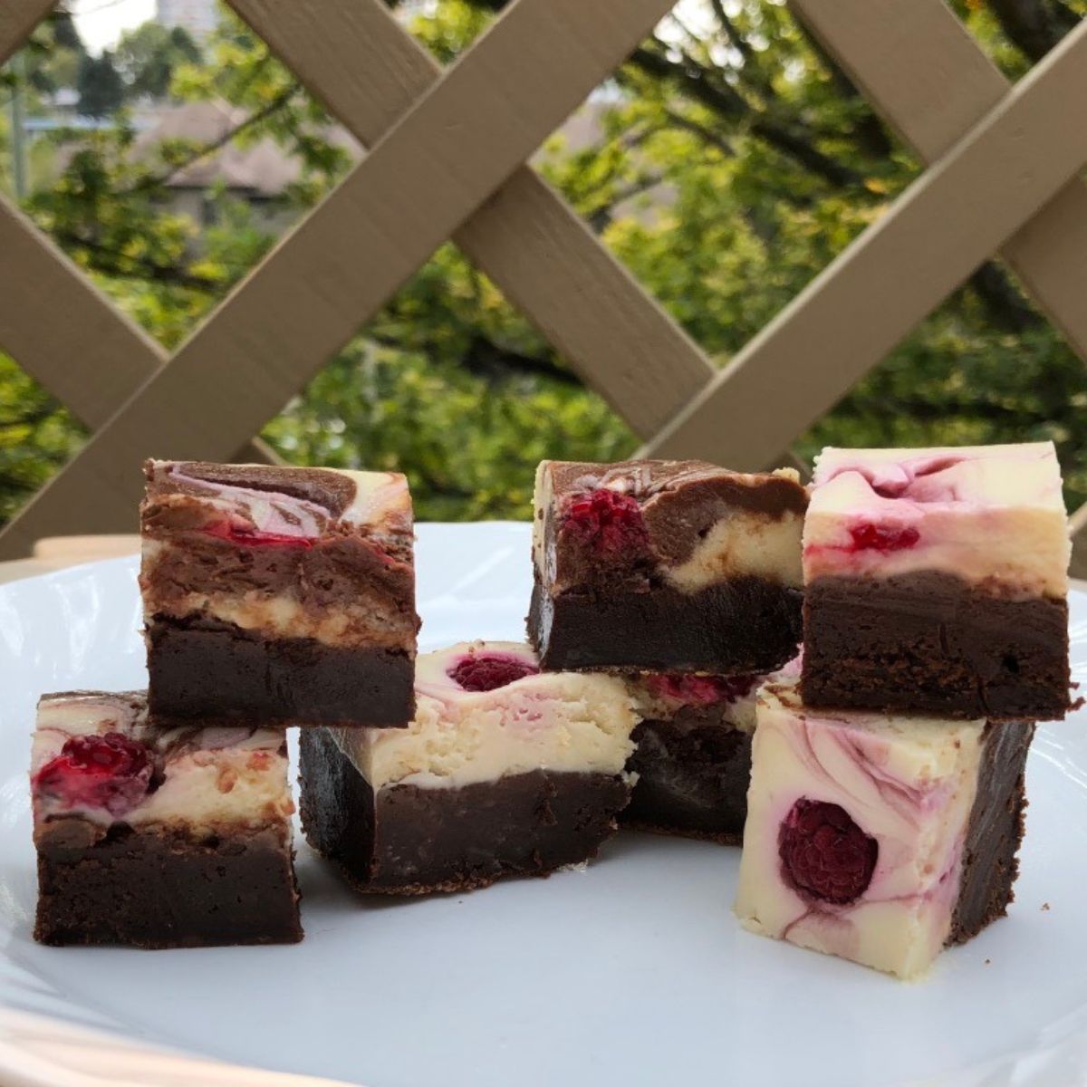 Raspberry Swirl Cheesecake Brownies cut on a plate and ready to eat.