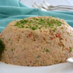A moulded Rice Salad garnished with strips of roasted red pepper and sprinkled with parsley.