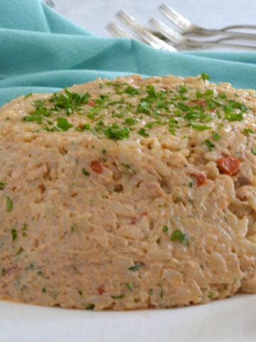 A moulded Rice Salad garnished with strips of roasted red pepper and sprinkled with parsley.