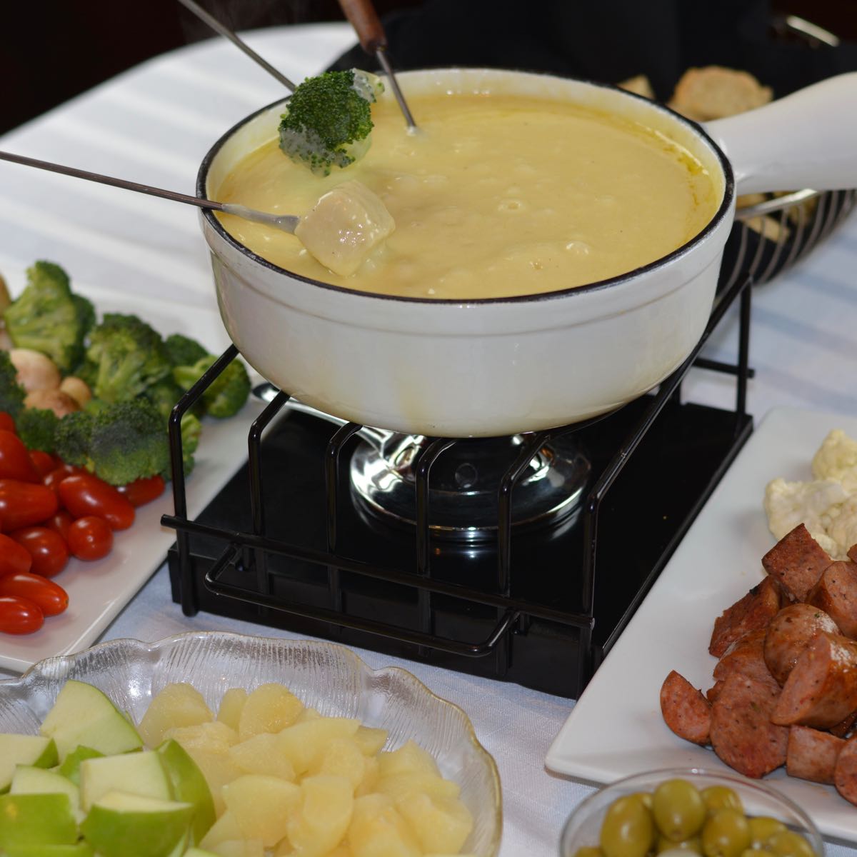 A Cheese Fondue pot surrounded by gluten free foods for dipping.