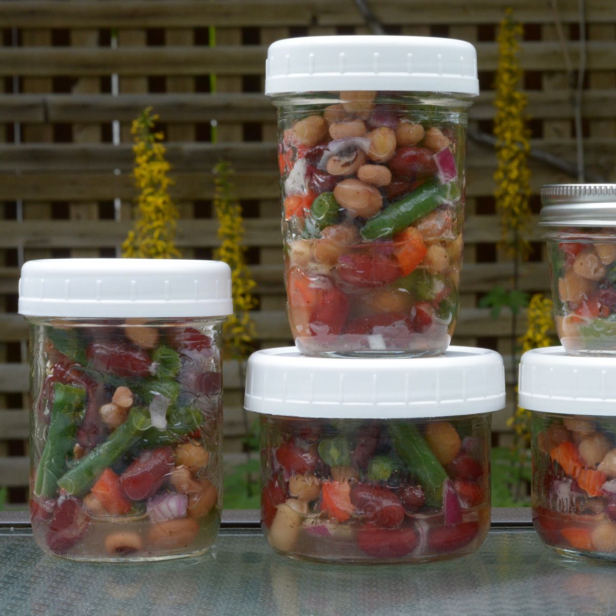 Several Mason Jars of different sizes filled with Bean Salad.