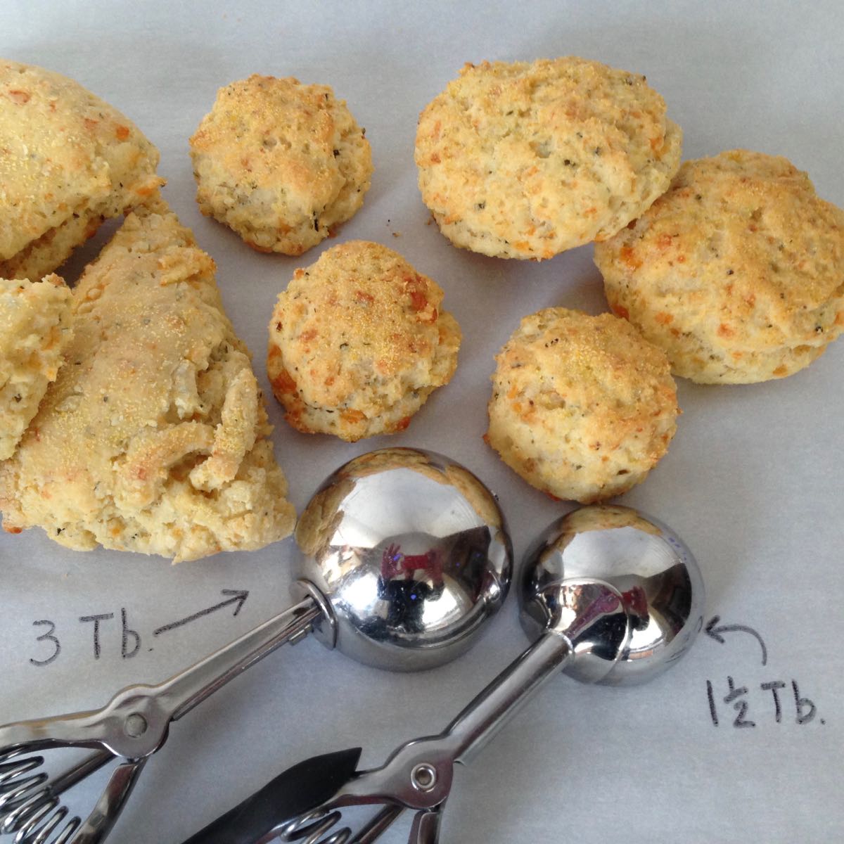 Three sizes of Pesto Cheddar Biscuits: round ones, small appetizer size and larger wedges.