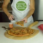 Cinde serving a piece of gluten free pizza off the wooden pizza peel.