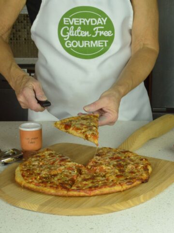 Cinde serving a piece of gluten free pizza off the wooden pizza peel.