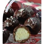 A tray of gluten free Nanaimo Balls sprinkled with crushed candy canes and a whole candy cane beside it.