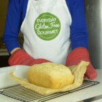 A loaf of gluten free millet bread on a wire rack.