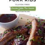 A cutting board with hoisin glazed pork ribs sprinkled with sesame seeds and chopped green onion with extra sauce on the side.