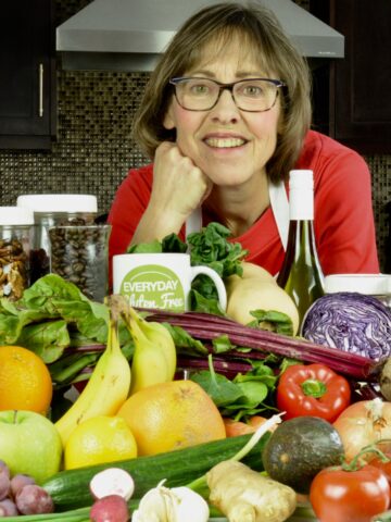 Cinde in her kitchen surrounded by an array of 30+ fruits, vegetables, legumes, nuts, seeds and more.