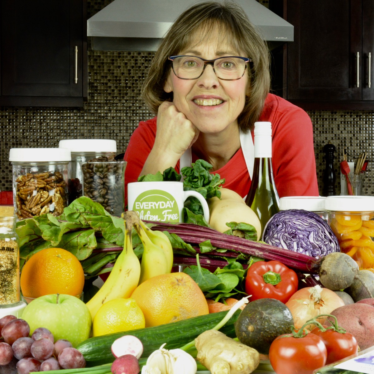 Cinde in her kitchen surrounded by an array of 30+ fruits, vegetables, legumes, nuts, seeds and more.
