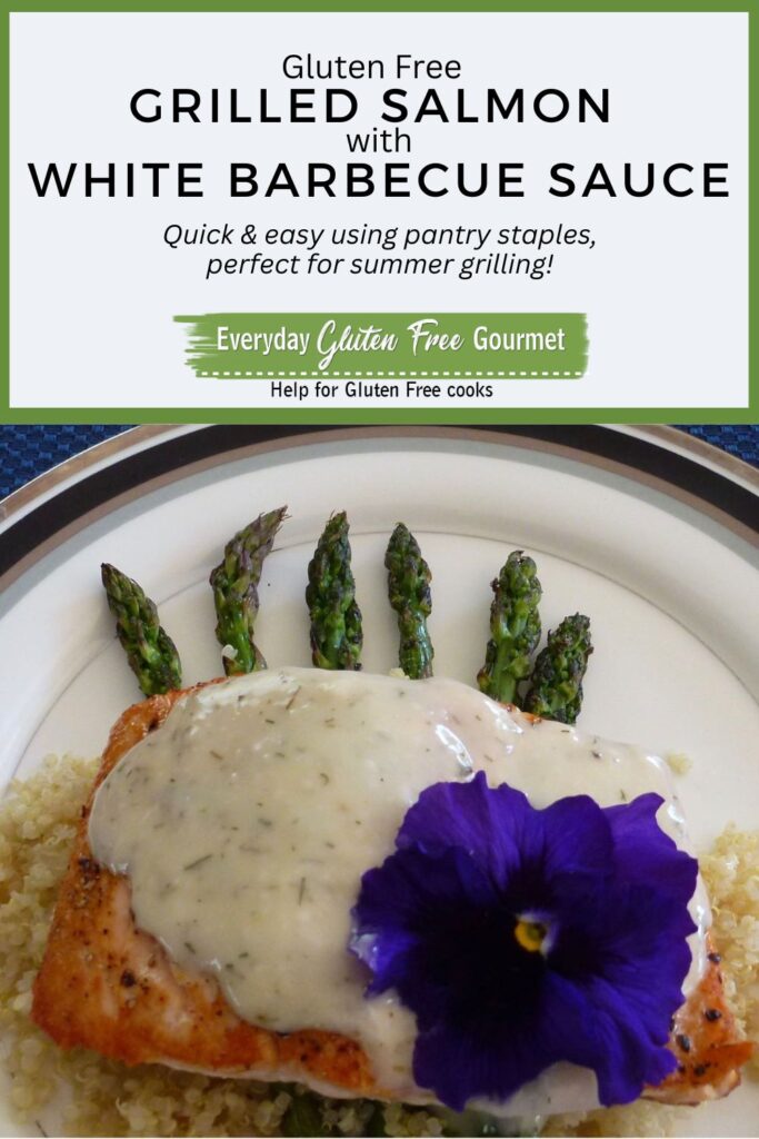 Grilled Salmon with White Barbecue Sauce on top of cooked asparagus spears with an edible pansy garnish.