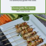 A platter of Vietnamese Lemongrass Chicken Skewers surrounded by lemongrass, carrots, cucumber and lemon wedges.
