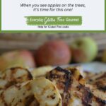 A platter of Grilled Mustard Chicken with Apple Rings in front of a row of red apples.