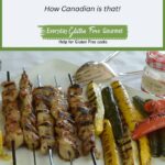 A platter with Crab Apple Jelly Glazed Chicken on skewers, grilled squash, peppers and small pieces of corn on the cob.