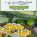 A serving dish filled with half cobs of corn sprinkled with feta cheese and topped with lime wedges.