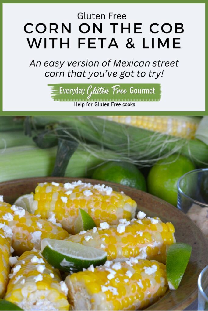 A serving dish filled with half cobs of corn sprinkled with feta cheese and topped with lime wedges.
