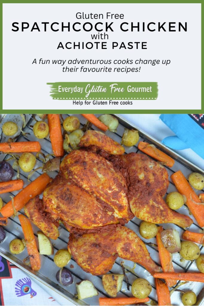 A tray with a cooked Spatchcock Chicken rubbed with achiote butter surrounded by roasted carrots and potatoes.