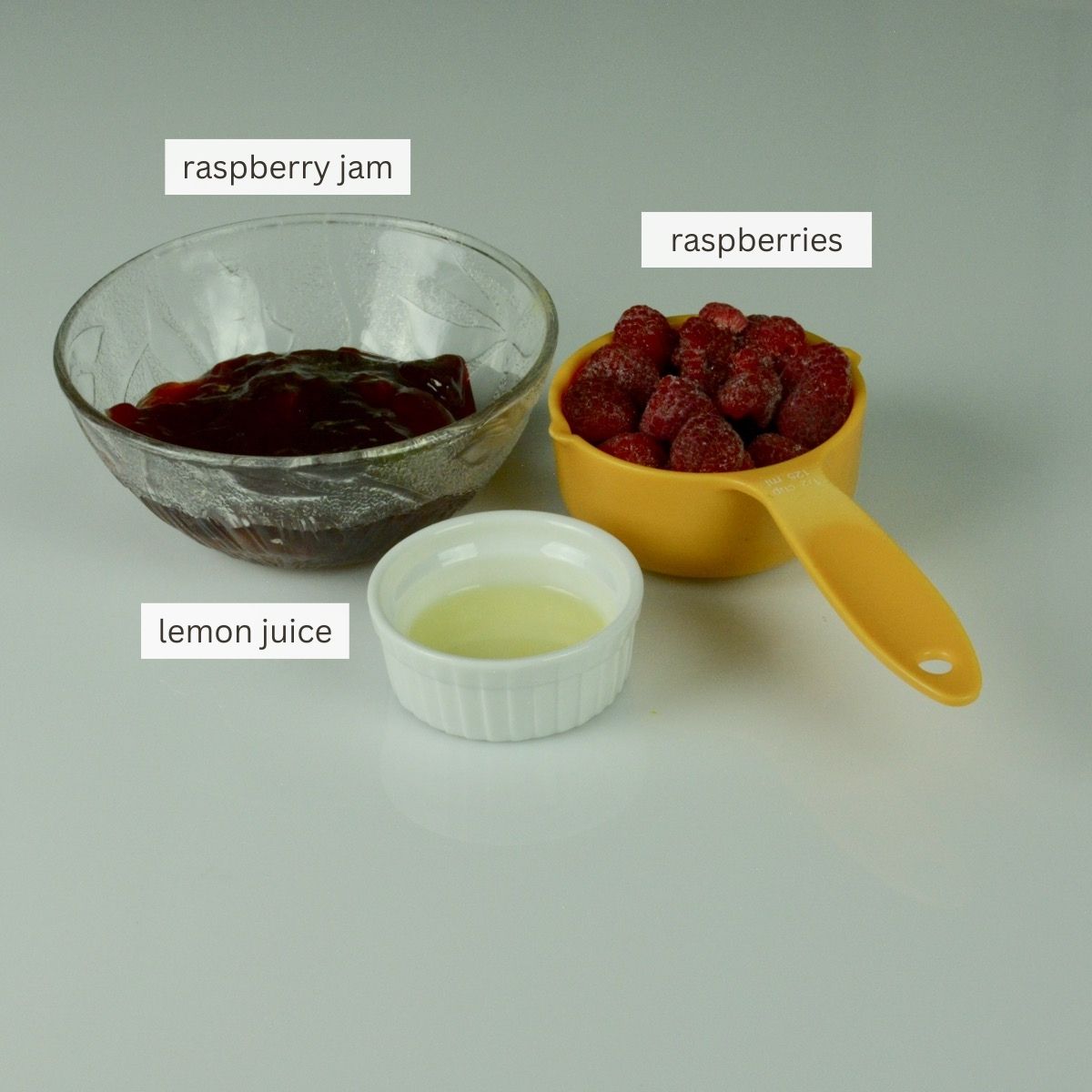 The filling ingredients for raspberry crumble bars; raspberry jam, whole raspberries and lemon juice.