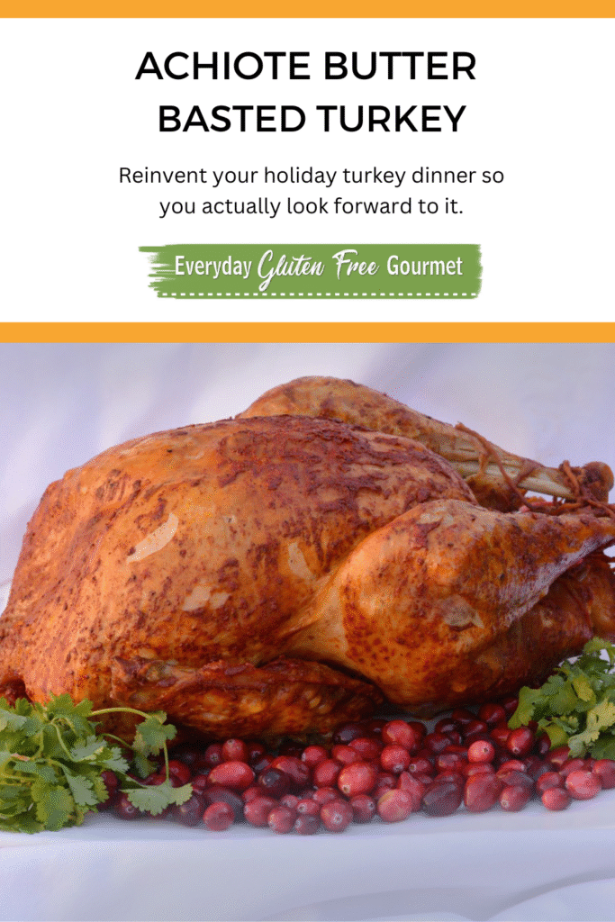 A whole Achiote Butter Basted Turkey on a platter surrounded by cranberries and cilantro.