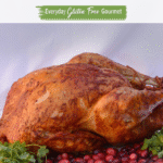 A whole Achiote Butter Basted Turkey on a platter surrounded by cranberries and cilantro.