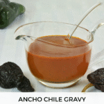 A gravy boat filled with Ancho Chile Gravy surrounded by fresh and dried chiles.