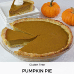 A whole gluten free Pumpkin Pie with one piece placed on a plate and 2 mini pumpkins beside it.