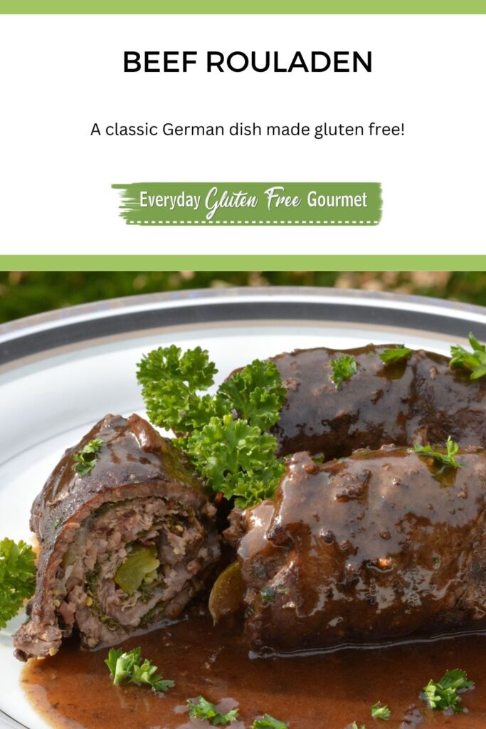 A plate with 3 rolls of Beef Rouladen covered in a rich red wine gravy and sprinkled with parsley.