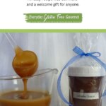 A jar of Homemade Caramel Sauce wrapped and labelled for a gift; beside a sauce boat with caramel sauce on a ladle dripping back into the dish.