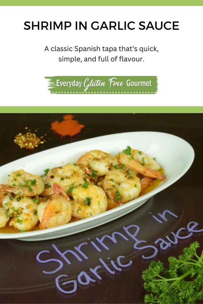 White plate with shrimp in garlic sauce sprinkled with parsley, in the background is garlic, chile flakes and paprika.