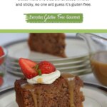 A piece of Gluten Free Sticky Date Pudding on a plate with caramel sauce dripping down the sides topped with whipped cream and a strawberry.