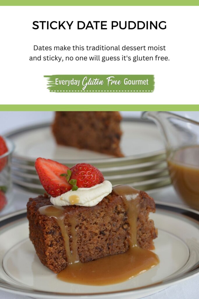 A piece of Gluten Free Sticky Date Pudding on a plate with caramel sauce dripping down the sides topped with whipped cream and a strawberry.