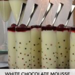 A tray of White Chocolate Mousse shots with raspberry sauce and a raspberry on top.