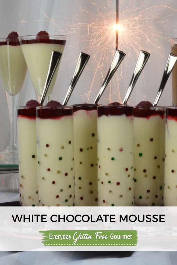 A tray of White Chocolate Mousse shots with raspberry sauce and a raspberry on top.